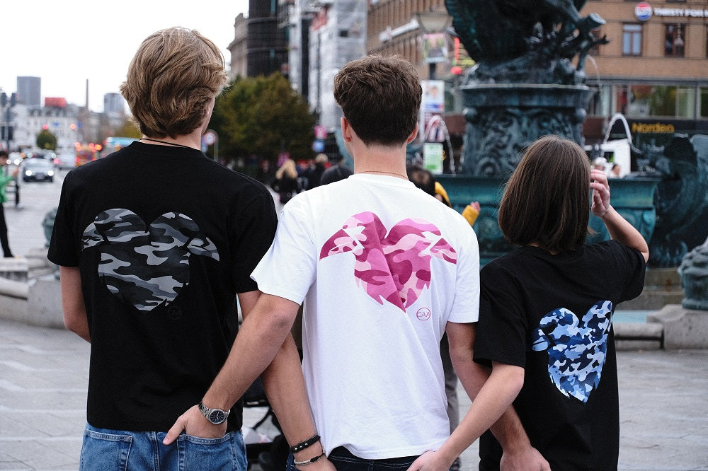 Three people wearing t-shirts with unique designs on the back, standing in an urban setting.