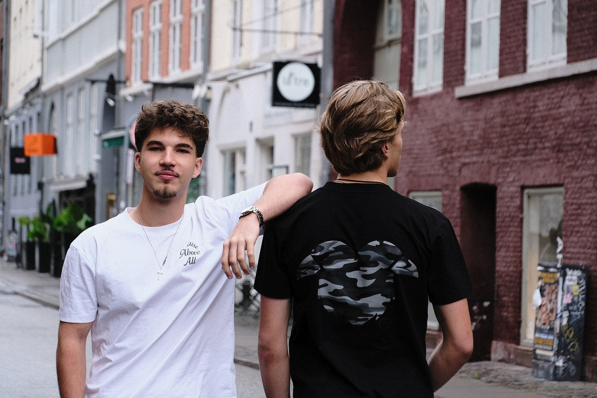 Two young men standing on a street with buildings in the background